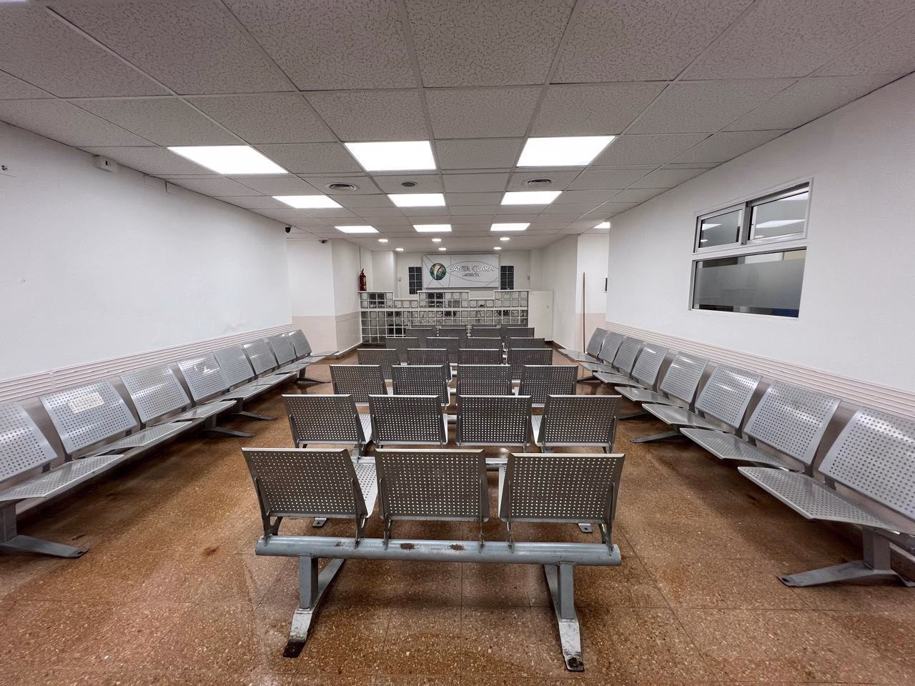 Sala de espera larga de la Clínica Santa Clara, con filas de asientos y piso existente