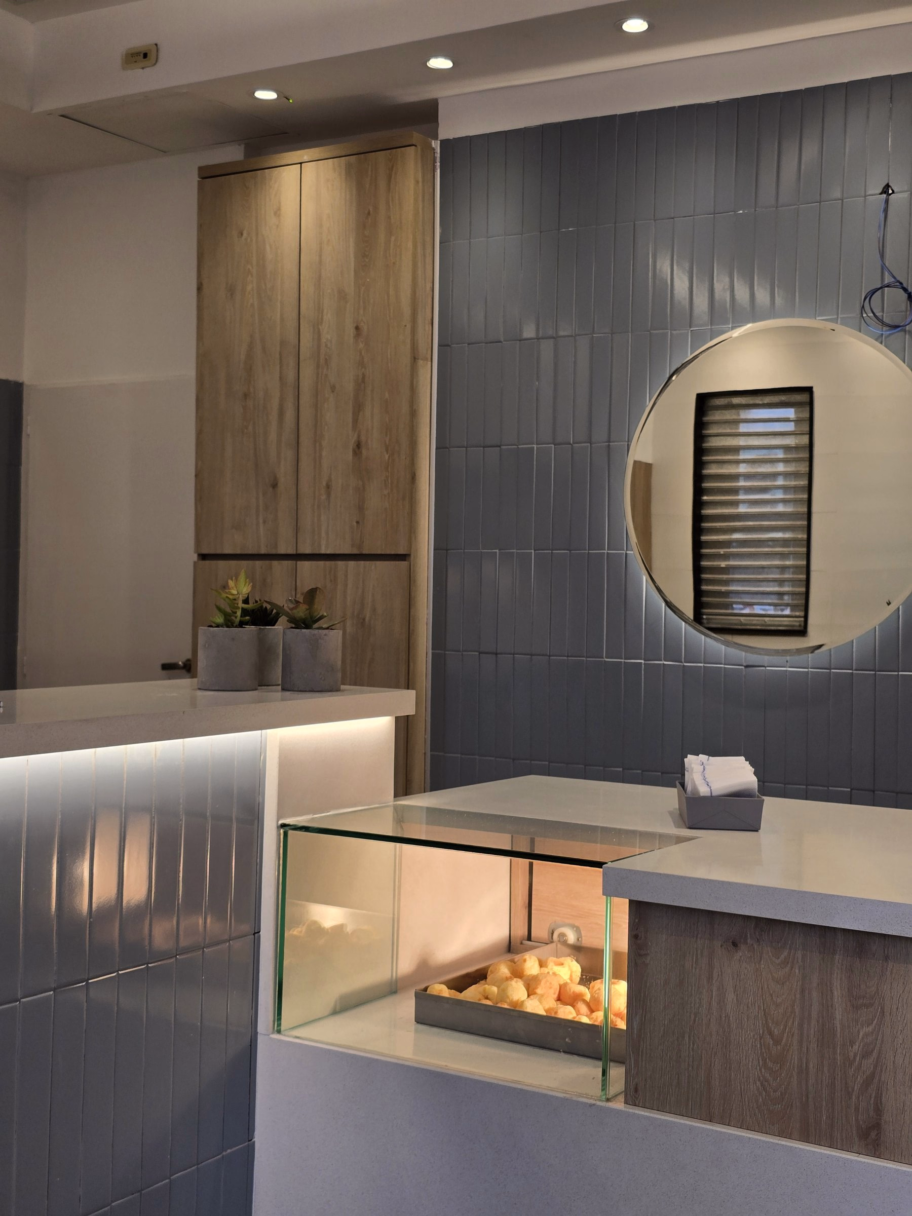 Detalle curvo de El Topo II, con revestimiento gris, madera y vitrina iluminada