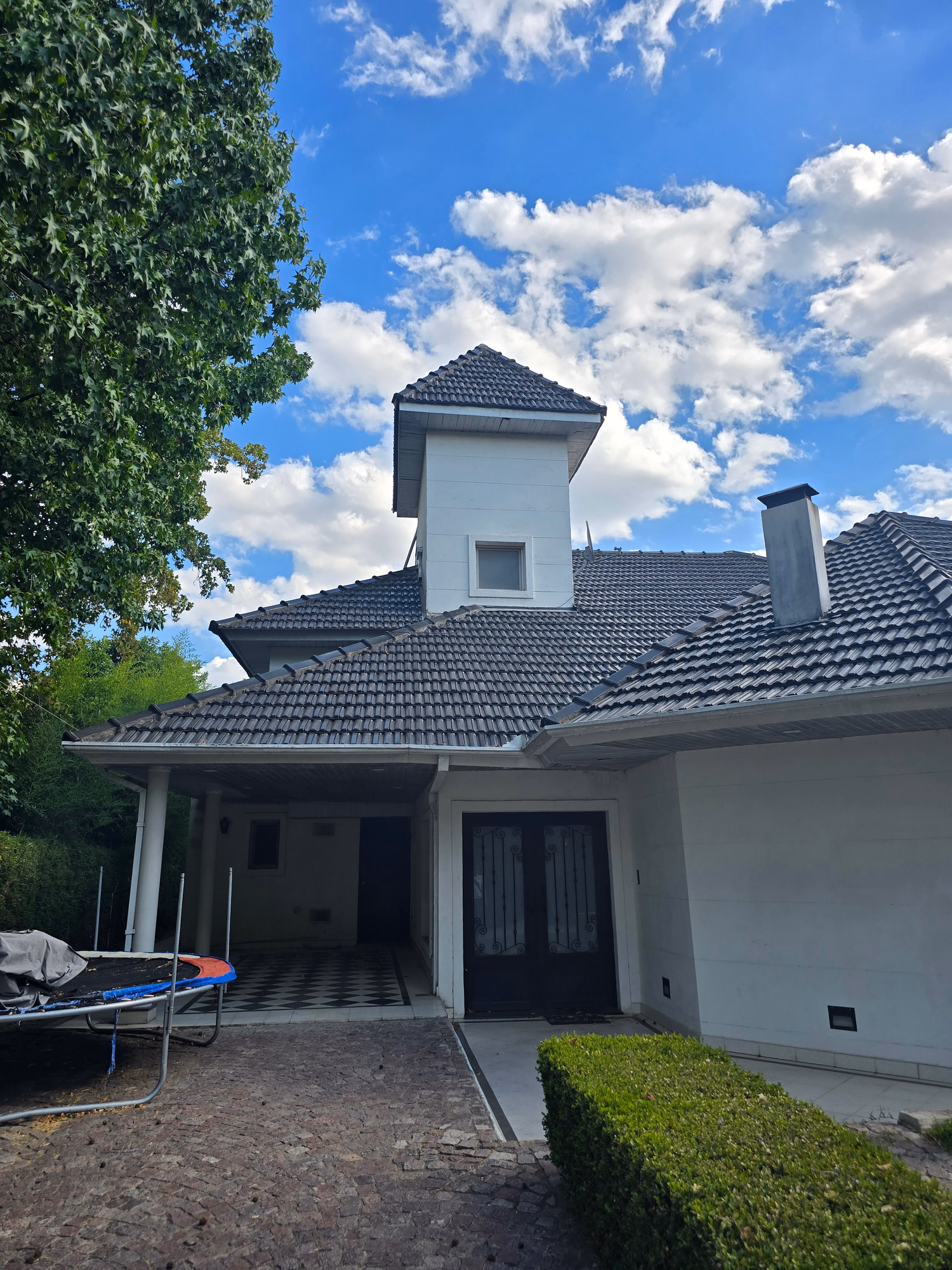 Fachada principal de Miraflores en Garín: casa blanca, techos de teja oscura, entrada y galería en damero