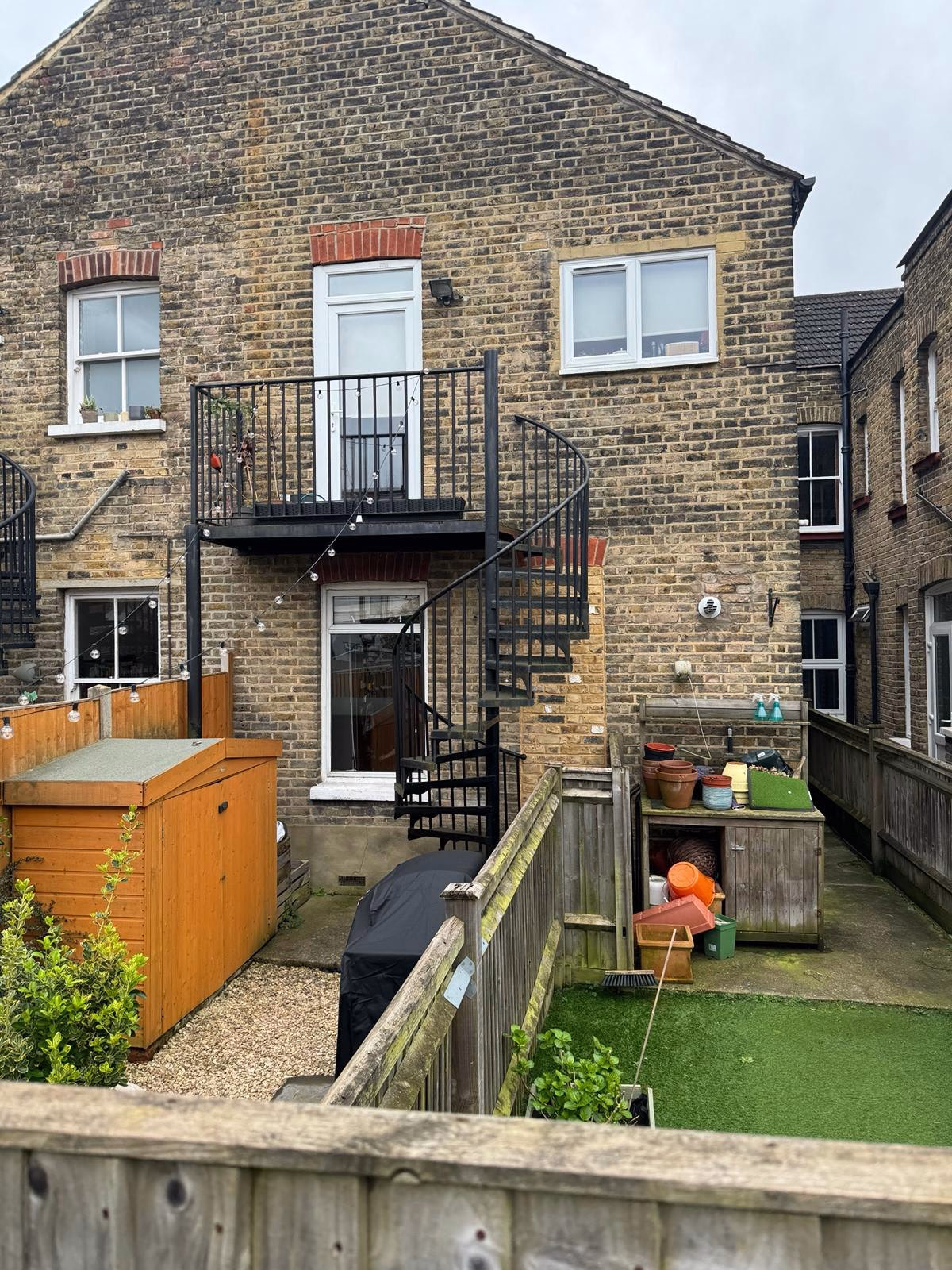 Fondo existente de Oxford Avenue en Wimbledon: ladrillo, balcón y la escalera metálica que ya está en el patio